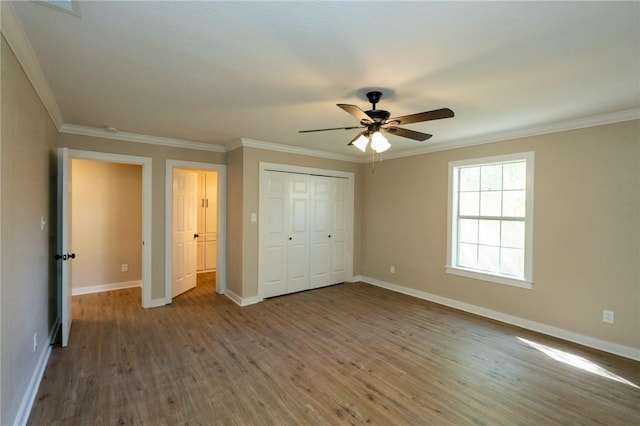 unfurnished bedroom featuring wood finished floors, a closet, ornamental molding, and baseboards