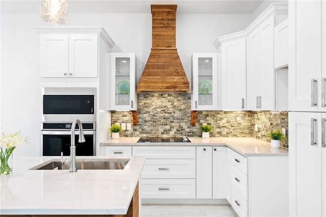 kitchen featuring premium range hood, white cabinets, sink, tasteful backsplash, and stainless steel appliances