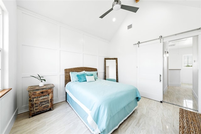 bedroom with a barn door, ceiling fan, and high vaulted ceiling