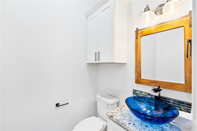 bathroom featuring vanity, tasteful backsplash, and toilet