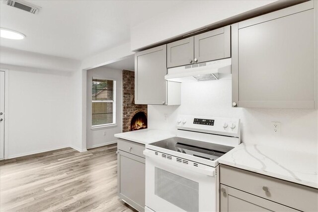 2108 Matagorda Dr, Portland, TX 78374 - kitchen featuring white electric range oven, under cabinet range hood, gray cabinets, light wood finished floors, and light stone counters