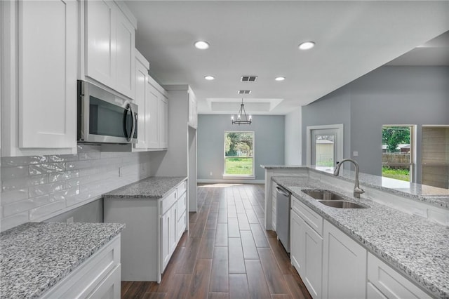 407 Main, Odem, TX 78370 - kitchen featuring stainless steel appliances, light stone counters, a tray ceiling, dark wood finished floors, and white cabinetry