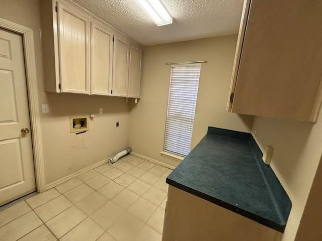 clothes washing area featuring gas dryer hookup, cabinets, washer hookup, a textured ceiling, and hookup for an electric dryer