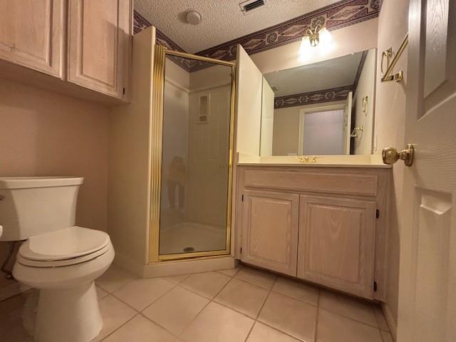 bathroom with tile patterned floors, a textured ceiling, toilet, a shower with door, and vanity