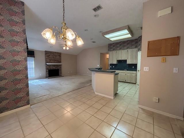 kitchen featuring decorative light fixtures, a brick fireplace, light tile patterned floors, tasteful backsplash, and a notable chandelier