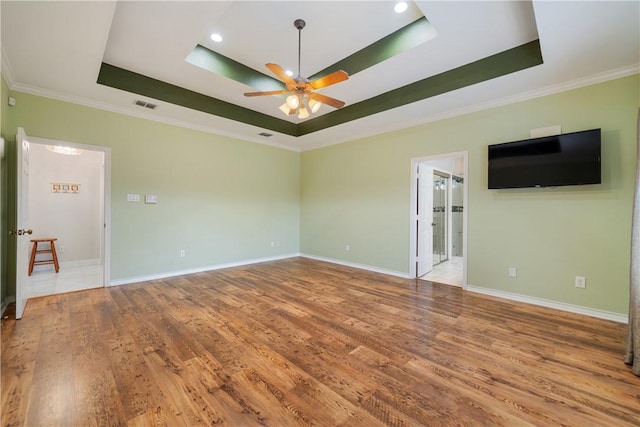 empty room with a tray ceiling, visible vents, and wood finished floors