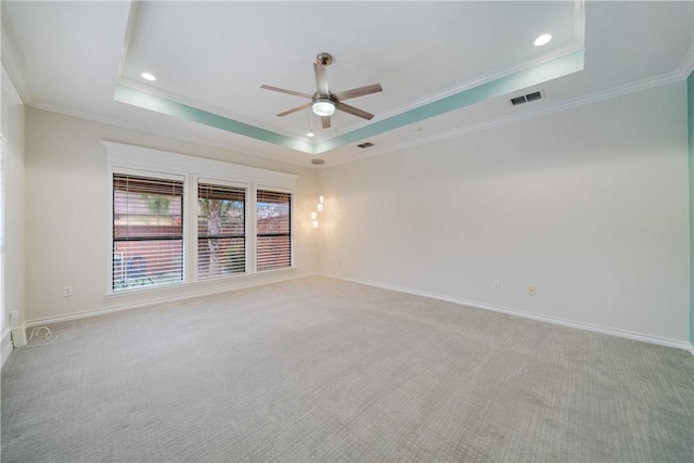 spare room featuring crown molding, a raised ceiling, light colored carpet, visible vents, and baseboards