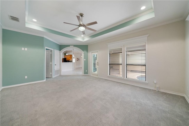 unfurnished room featuring arched walkways, a raised ceiling, and visible vents