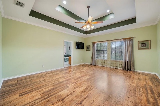 unfurnished room featuring baseboards, visible vents, a tray ceiling, and wood finished floors