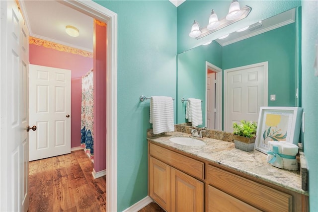 bathroom with baseboards, visible vents, ornamental molding, wood finished floors, and vanity