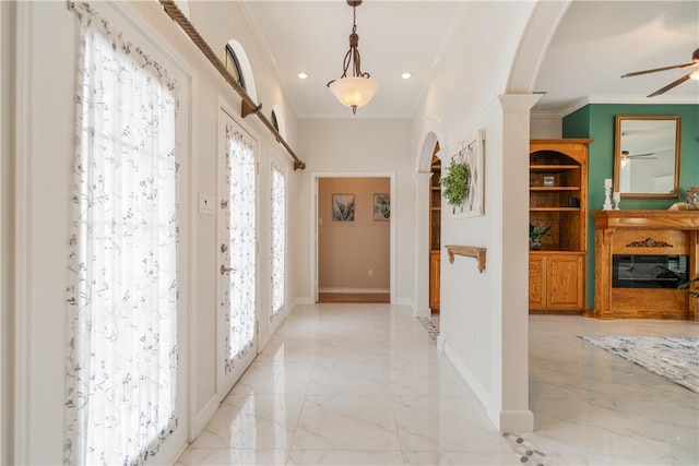 hallway with arched walkways, marble finish floor, crown molding, and baseboards