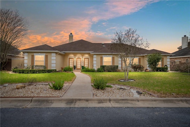 view of front of property featuring french doors, a chimney, a front yard, and stucco siding