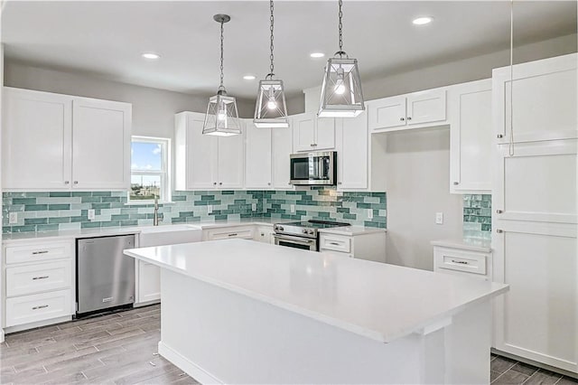 kitchen with light hardwood / wood-style floors, white cabinets, stainless steel appliances, and a kitchen island