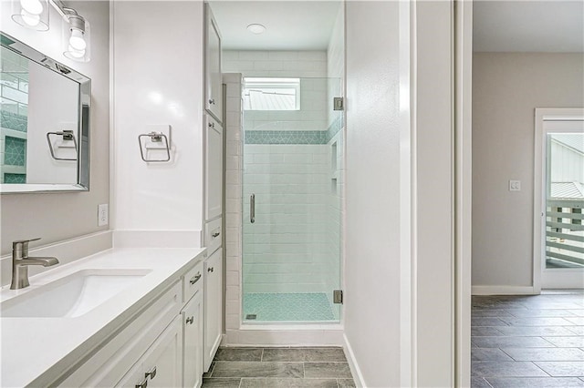 bathroom featuring a shower with door and vanity