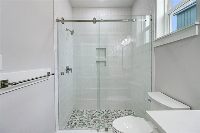 bathroom featuring toilet and a shower with shower door