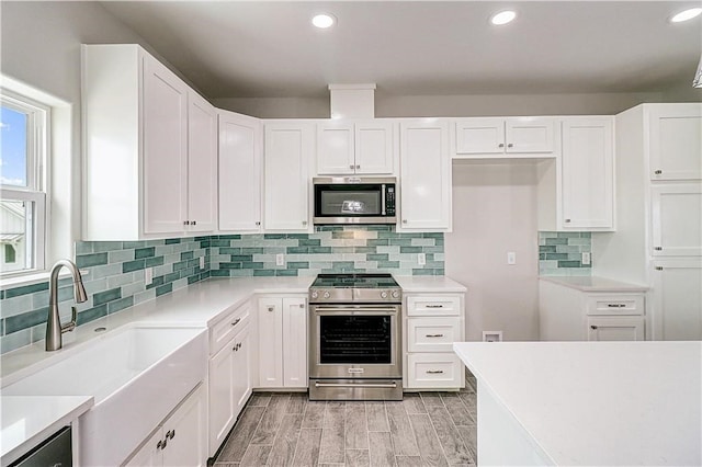 kitchen featuring backsplash, stainless steel appliances, sink, light hardwood / wood-style floors, and white cabinetry