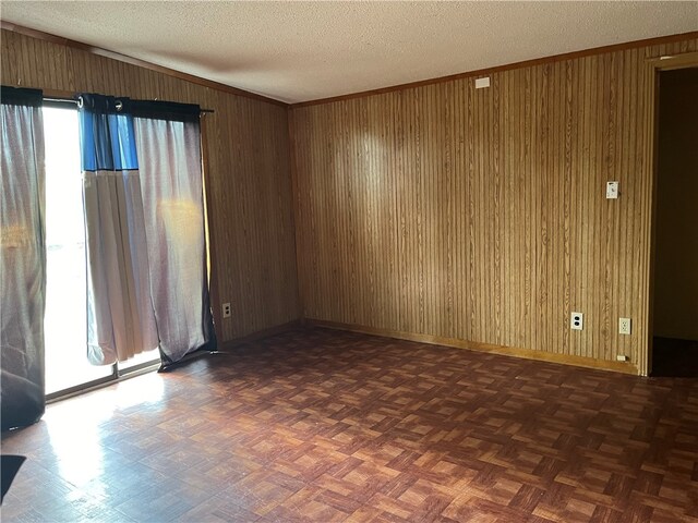 unfurnished room featuring a textured ceiling, dark parquet flooring, and wooden walls