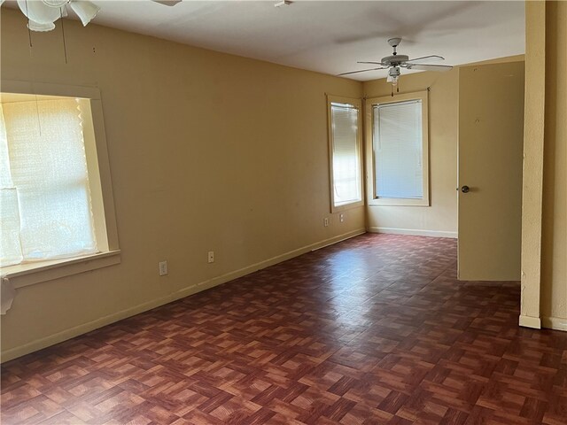 empty room with ceiling fan and dark parquet flooring