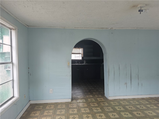 unfurnished room with a textured ceiling and wooden walls