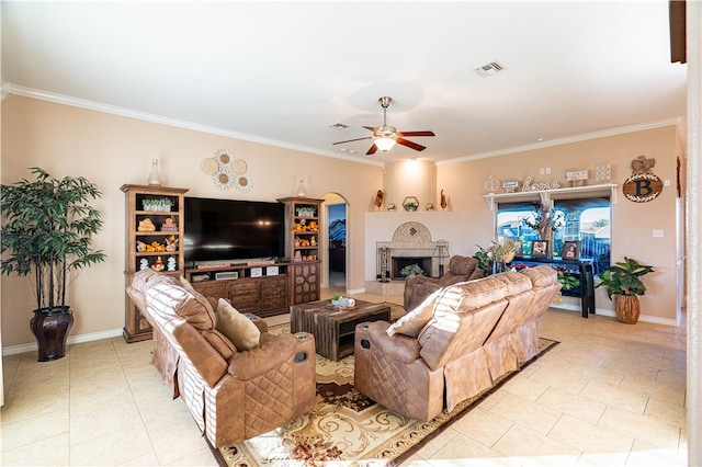 tiled living room featuring ornamental molding, a fireplace, and ceiling fan