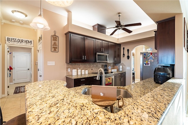 kitchen featuring stainless steel appliances, dark brown cabinetry, kitchen peninsula, light tile patterned floors, and backsplash