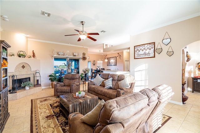 living room with ornamental molding, ceiling fan, and a tile fireplace