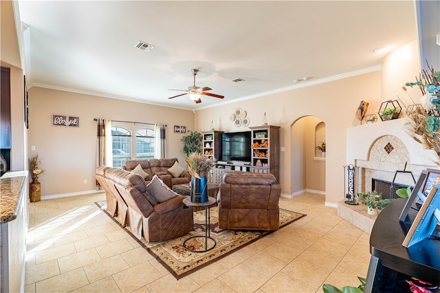 tiled living room with a tile fireplace, ceiling fan, and crown molding