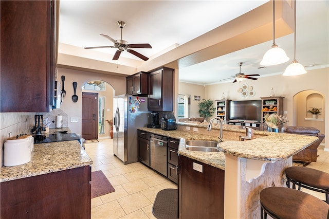 kitchen with backsplash, appliances with stainless steel finishes, hanging light fixtures, sink, and a kitchen breakfast bar