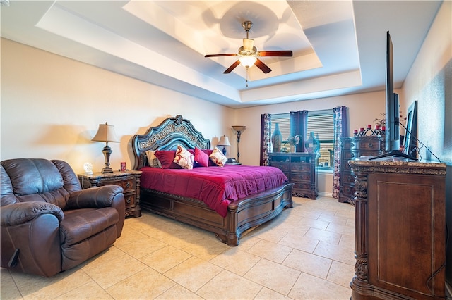 tiled bedroom with a tray ceiling and ceiling fan