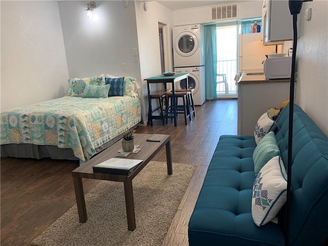 bedroom featuring dark hardwood / wood-style flooring and stacked washing maching and dryer