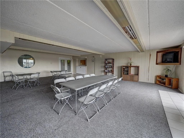 carpeted dining area featuring a textured ceiling and beam ceiling