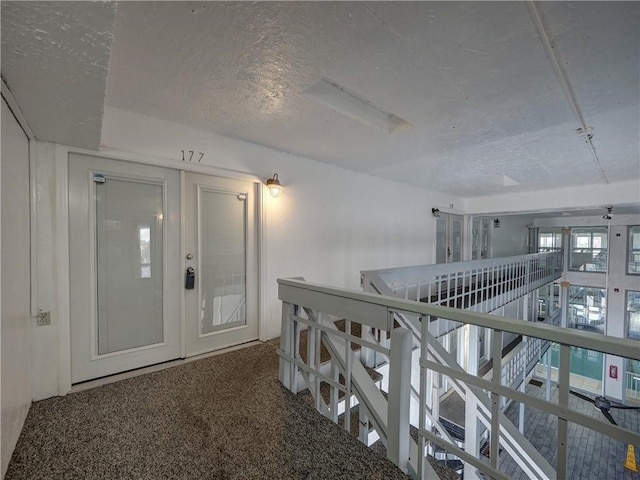 hallway with carpet flooring and a textured ceiling