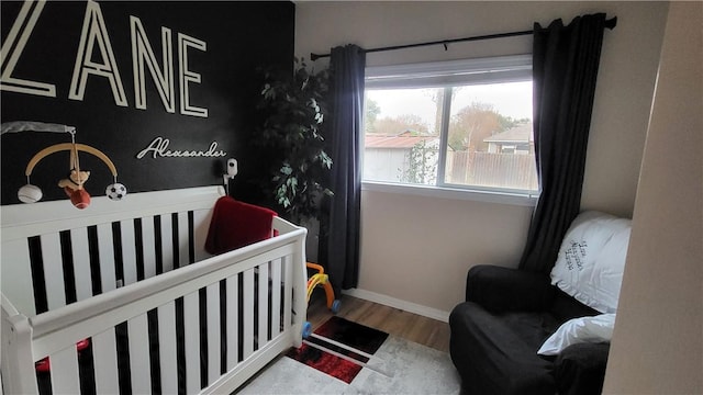 bedroom with wood-type flooring and a nursery area