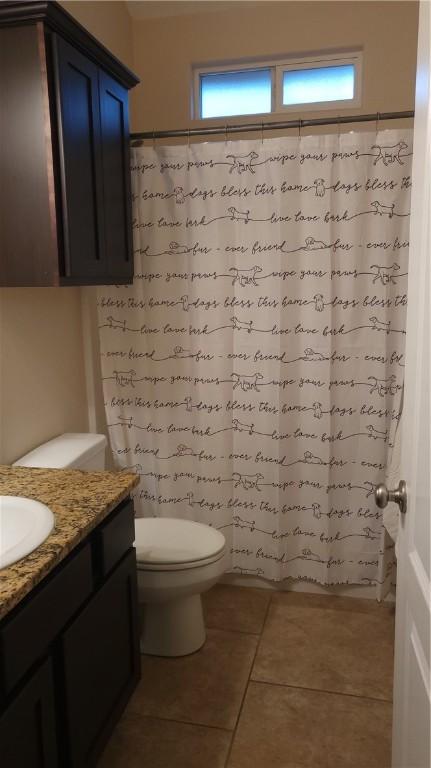 bathroom with toilet, vanity, and tile patterned floors