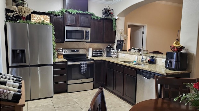 kitchen with appliances with stainless steel finishes, sink, ornamental molding, and light tile patterned flooring