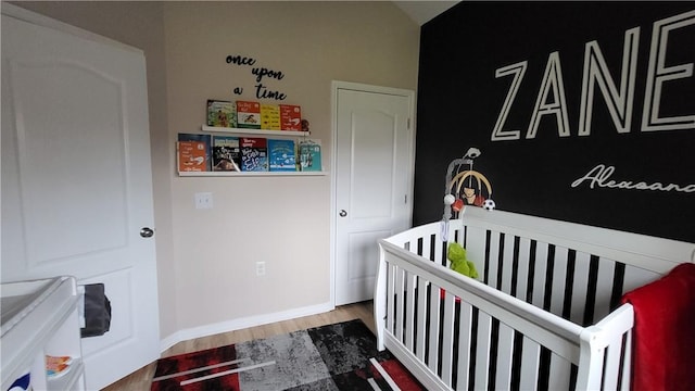 bedroom featuring hardwood / wood-style flooring and a crib