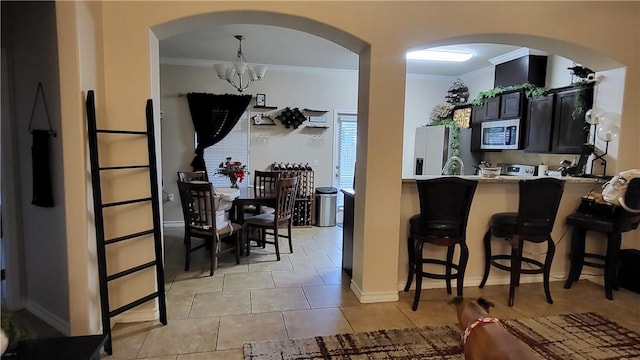 kitchen featuring appliances with stainless steel finishes, an inviting chandelier, kitchen peninsula, light tile patterned floors, and a breakfast bar area