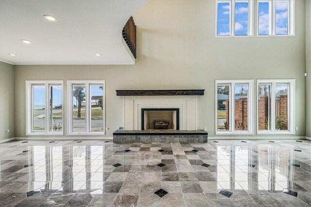 unfurnished living room featuring recessed lighting, a fireplace with raised hearth, marble finish floor, and baseboards