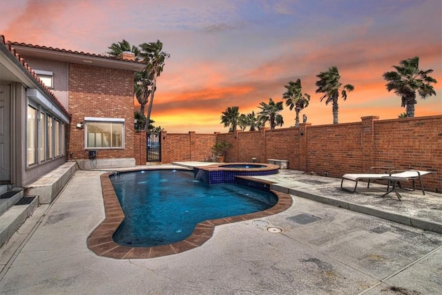 pool at dusk with a pool with connected hot tub, a patio, and fence