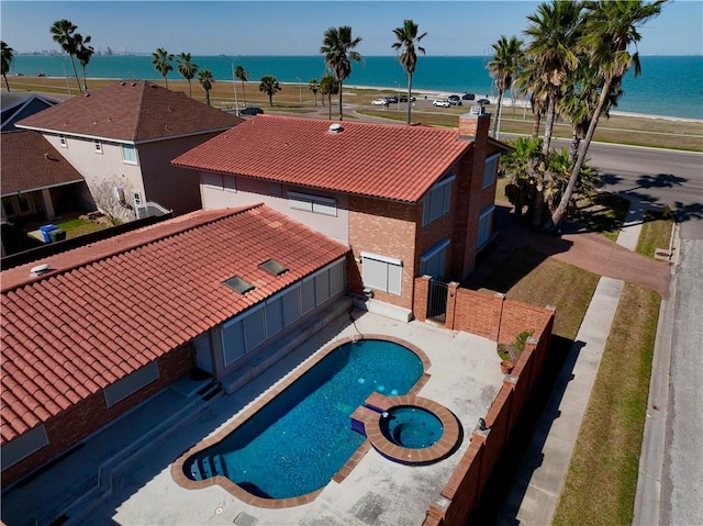 view of pool with a patio, a pool with connected hot tub, a fenced backyard, and a water view