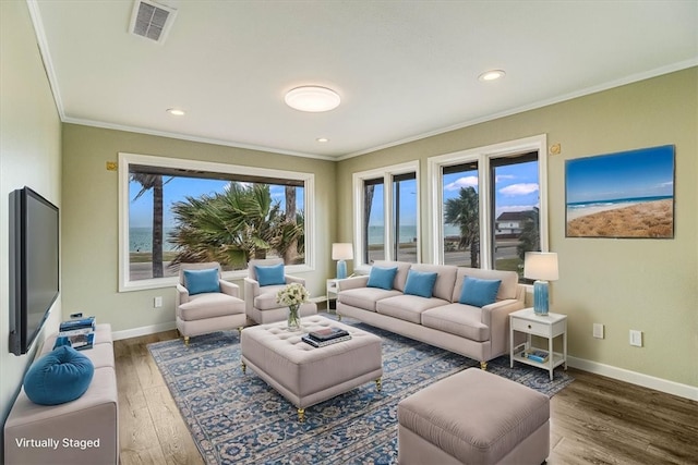 living area with visible vents, ornamental molding, baseboards, and wood finished floors