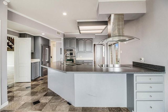 kitchen featuring gray cabinets, appliances with stainless steel finishes, a peninsula, and island range hood