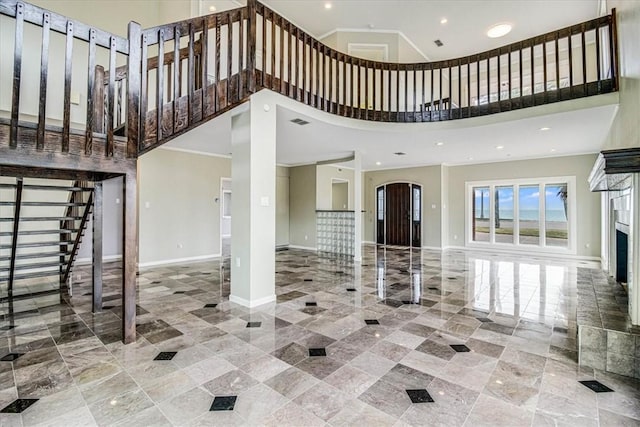 interior space with stairs, crown molding, baseboards, and a towering ceiling