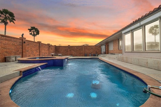 pool at dusk with a patio area, a fenced in pool, an in ground hot tub, and a fenced backyard