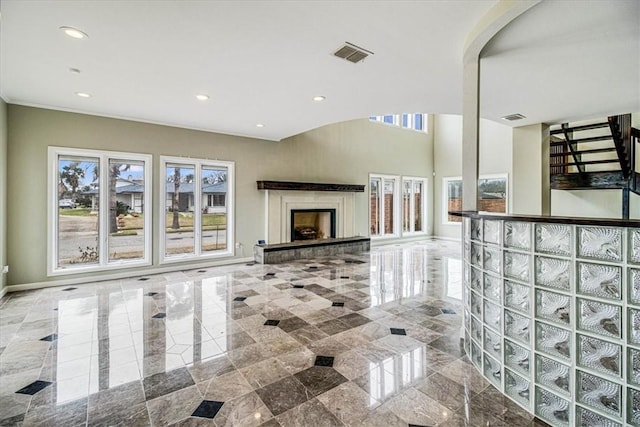 living room with a wealth of natural light, visible vents, baseboards, and a fireplace with raised hearth