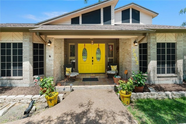 7033 Chiswick Dr, Corpus Christi, TX 78413 - entrance to property featuring brick siding, a porch, and a shingled roof