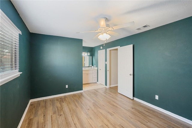 unfurnished bedroom featuring ceiling fan, ensuite bath, and light hardwood / wood-style flooring