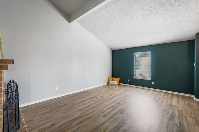 unfurnished room with lofted ceiling with beams, hardwood / wood-style floors, a textured ceiling, and a fireplace