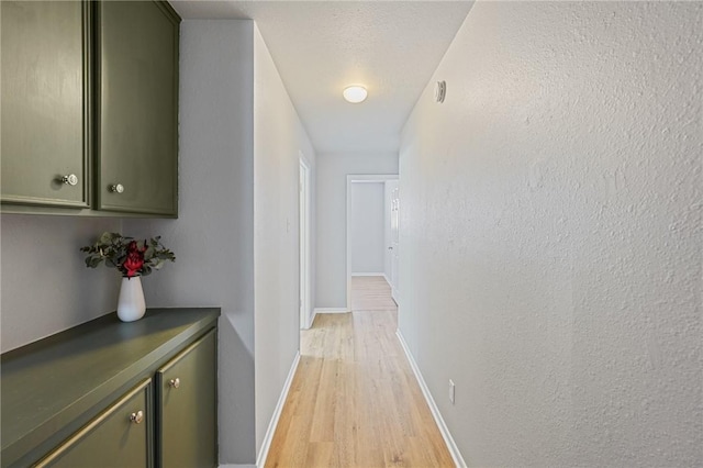 hallway with light hardwood / wood-style flooring and a textured ceiling