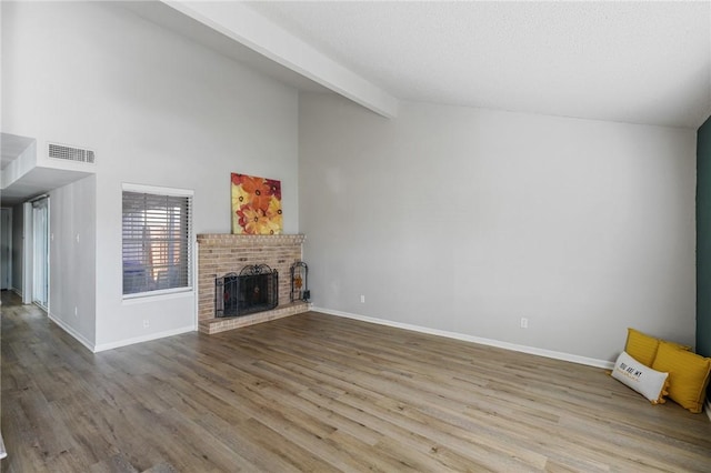 unfurnished living room with a fireplace, lofted ceiling with beams, and light wood-type flooring